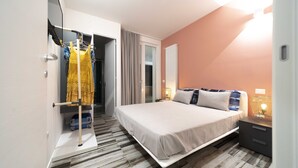 Una habitación de hotel moderna con cama, armario, mesita de noche y lámpara.