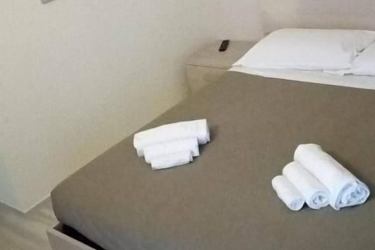 Habitación de hotel con cama, mesita de noche y televisor montado en la pared.