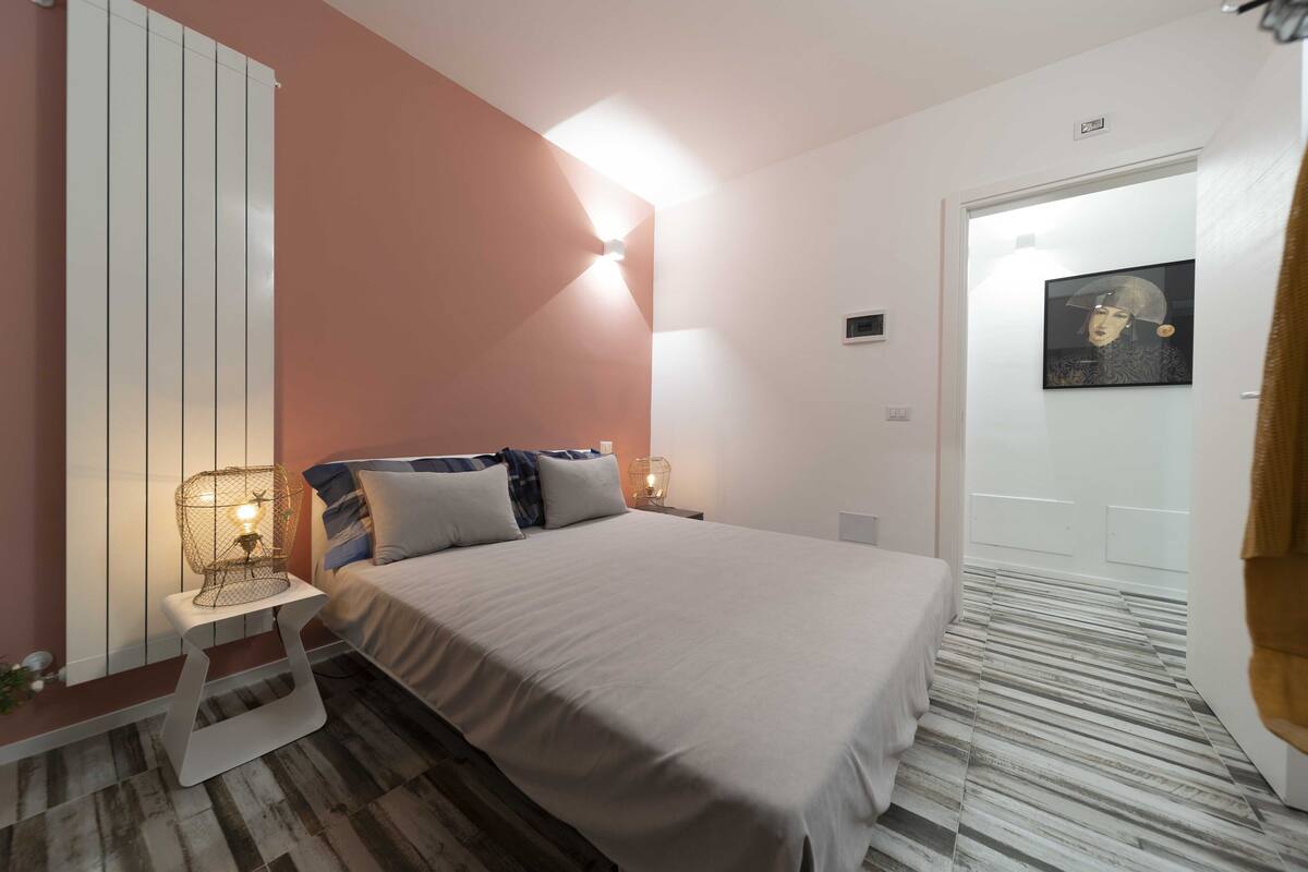 Un dormitorio con cama, mesita de noche y lámpara de pared.