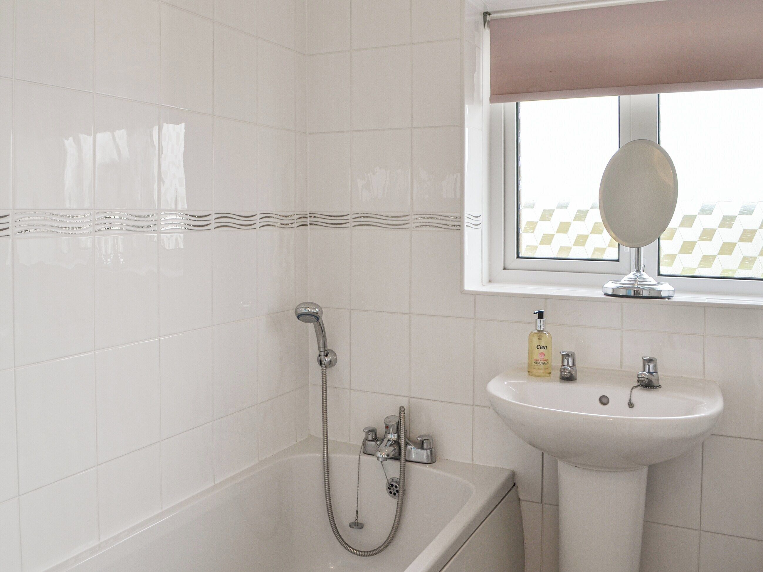 Une salle de bain avec une baignoire, un lavabo et une fenêtre avec un miroir.