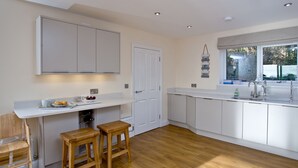 A modern kitchen with white cabinetry, a wooden countertop, and a window with a view.