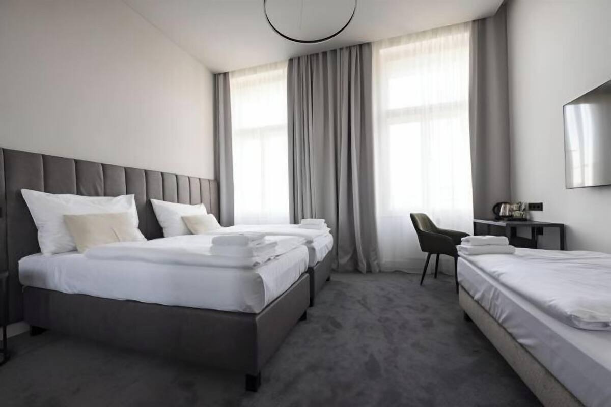 Una habitación de hotel con una cama grande, una cama más pequeña, un escritorio y una silla.