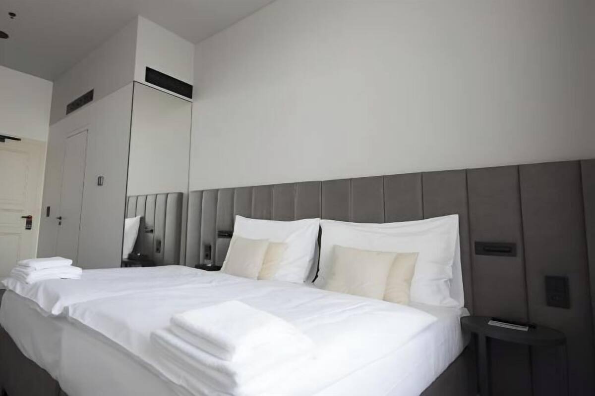 Una habitación de hotel moderna con una cama grande, una mesita de noche y un armario.