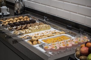 Buffet com diversos alimentos, incluindo doces, sobremesas e bebidas à base de frutas.