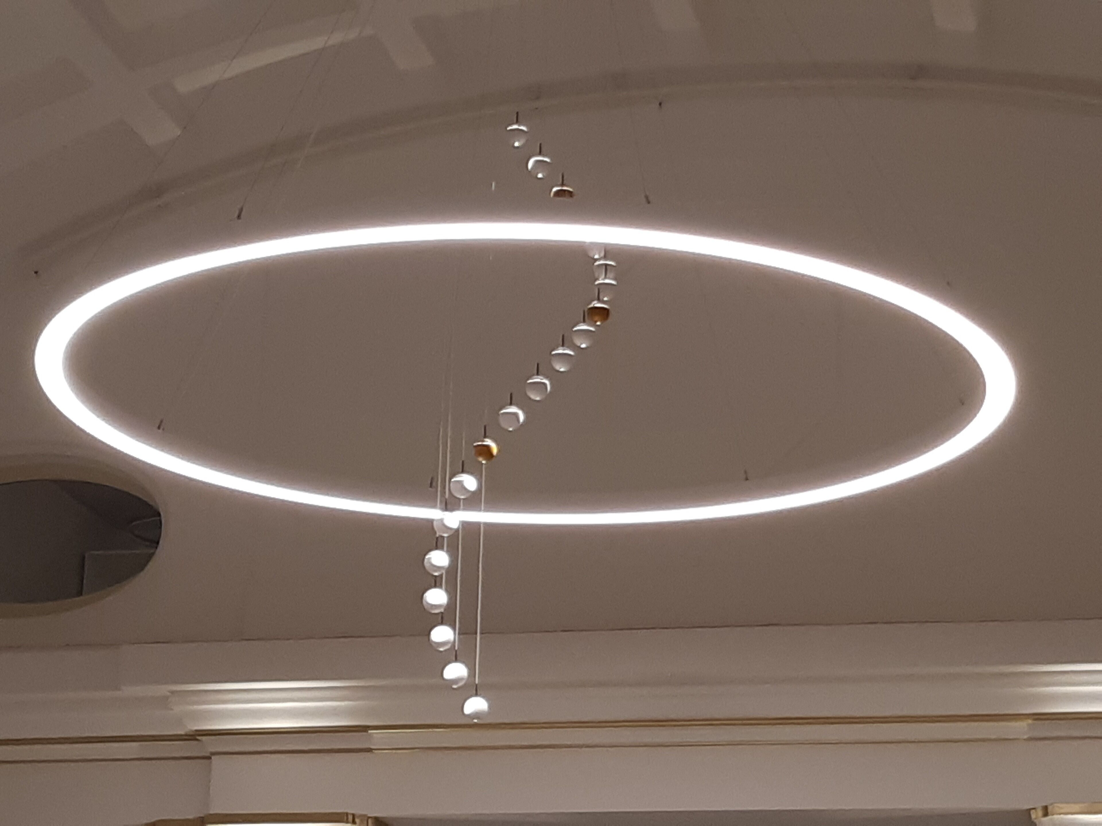 A ceiling with a circular light fixture and hanging spherical elements.