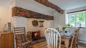 A rustic interior with a stone wall, wooden furniture, a fireplace, and a dining area. - 4 bedroom accommodation in Llandeilo (Llandeilo)