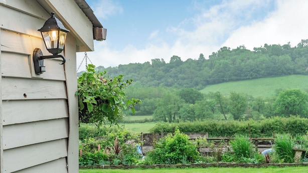 A house with a hanging planter and a lantern on the exterior wall. - 4 bedroom accommodation in Llandeilo (Llandeilo)