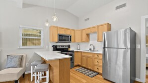 Una cucina moderna con mobili in legno, un frigorifero in acciaio inox, un forno a microonde e un forno integrato.