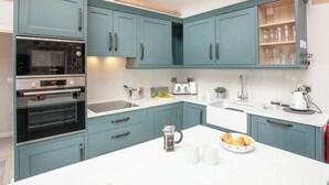 A kitchen with teal cabinets, a Bosch oven, a coffee maker, and a bowl of fruit on the island. - 2 bedroom accommodation in Southwood, near Glastonbury (Southwood, near Glastonbury)