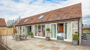 A stone house with a tiled roof, large sliding glass doors, and a patio with outdoor furniture. - 2 bedroom accommodation in Southwood, near Glastonbury (Southwood, near Glastonbury)