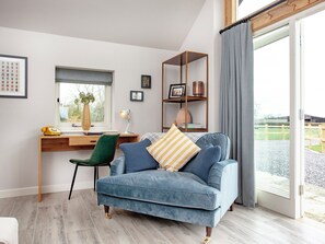 Een moderne woonkamer met een blauwe bank, een houten bureau en een groot raam.