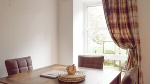 A dining area with a wooden table, two chairs, a woven placemat, and a window with plaid curtains. - 2 bedroom accommodation in Campsie Fells nr Fintry (Campsie Fells nr Fintry)