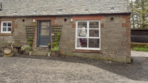 A stone cottage with a slate roof, a front door, and a window with a curtain. - 2 bedroom accommodation in Campsie Fells nr Fintry (Campsie Fells nr Fintry)