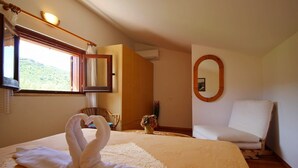 Ein Hotelzimmer mit Bett, Stuhl, Spiegel und einem Fenster mit Vorhängen.