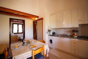 A dining area with a table set for four, a washing machine, and a kitchen with white cabinets and a countertop.