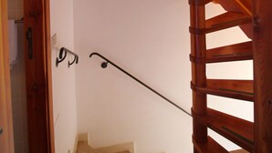 Eine Holztreppe mit Geländer und einer Tür am Obergeschoss.