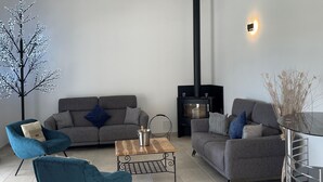 Un salon moderne comprenant un canapé, deux fauteuils, une table basse, une cheminée et un arbre décoratif.