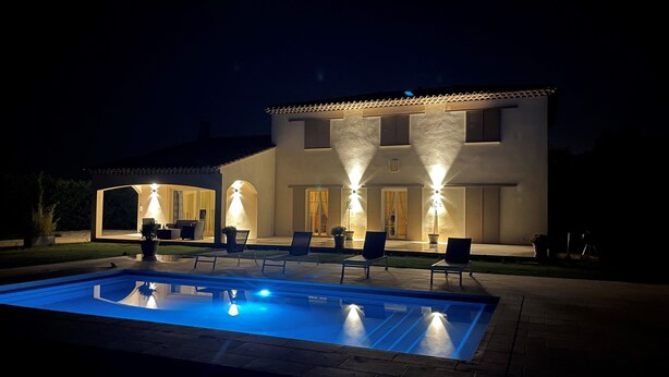 Une maison à deux étages avec une piscine et un espace extérieur aménagé pour se détendre.
