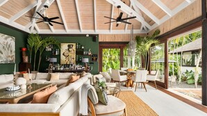 Un vaste espace de vie doté d’un haut plafond, d’un grand canapé, d’une table à manger et d’un coin bar agrémenté de diverses bouteilles et décorations.