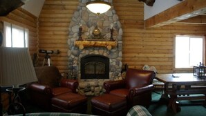 A log cabin interior with a stone fireplace, leather chairs, and a table. - Cabin, 4 Bedrooms + Loft, 4.5 Baths, (Sleeps 8-12) Mountain views with trails (Oakley)