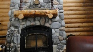 A stone fireplace with a log shelf, a hanging light fixture, and a mounted deer head. - Cabin, 4 Bedrooms + Loft, 4.5 Baths, (Sleeps 8-12) Mountain views with trails (Oakley)