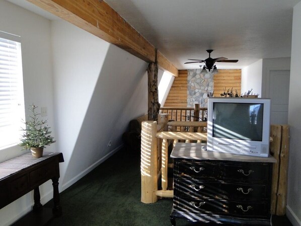 A room with a wooden ceiling, a TV on a dresser, a small Christmas tree, and a staircase. - Cabin, 4 Bedrooms + Loft, 4.5 Baths, (Sleeps 8-12) Mountain views with trails (Oakley)