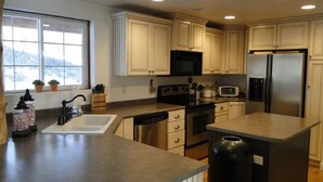 A modern kitchen with light wooden cabinets, stainless steel appliances, a large window, and a view of the outdoors. - Cabin, 4 Bedrooms + Loft, 4.5 Baths, (Sleeps 8-12) Mountain views with trails (Oakley)