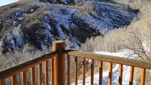 A wooden deck with a view of a snow-covered mountain. - Cabin, 4 Bedrooms + Loft, 4.5 Baths, (Sleeps 8-12) Mountain views with trails (Oakley)