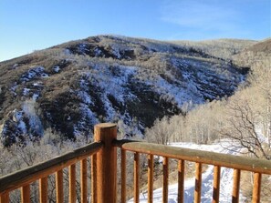 A wooden deck with a view of a snow-covered mountain. - Cabin, 4 Bedrooms + Loft, 4.5 Baths, (Sleeps 8-12) Mountain views with trails (Oakley)