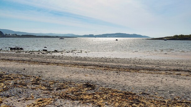 Ein Strand mit felsigem Ufer und ruhigem Wasser.