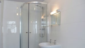 A modern bathroom with a glass-enclosed shower, a white sink, and a mirror above the sink. - 3 bedroom accommodation in Embleton (Embleton)