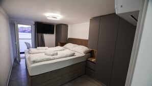 A modern bedroom with a bed, bedside tables, a TV, and a wardrobe. - Studio Apartment Direkt am Strand (Baška)