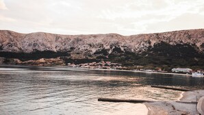 A coastal town with a mountain backdrop, calm waters, and a pier. - Studio Apartment Direkt am Strand (Baška)