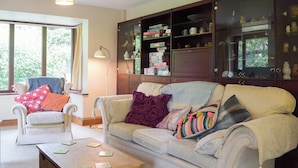 A living room with a sofa, armchairs, a coffee table, and a cabinet with glass doors.