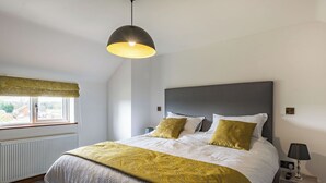 Un dormitorio con cama, mesita de noche, lámpara y ventana con vistas.