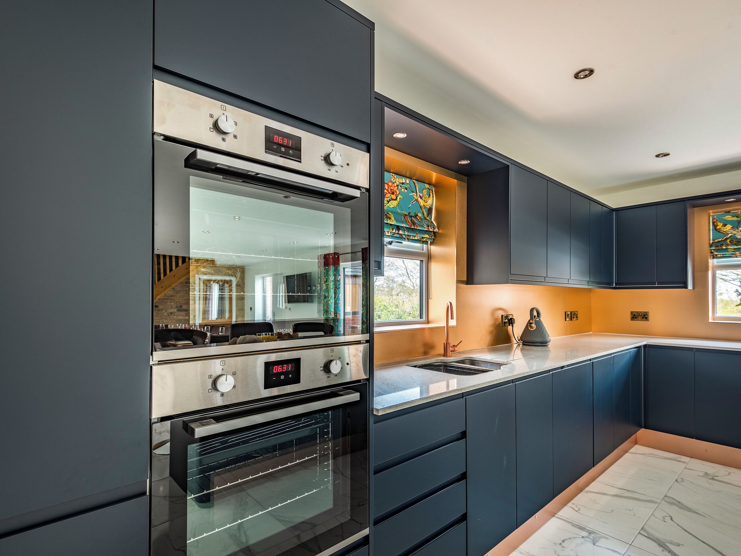 Una cocina moderna con armarios oscuros, una estufa de acero inoxidable y un amplio ventanal con vistas.