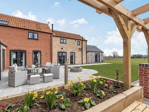 A brick house with a patio, outdoor seating, and flower beds. - 5 bedroom accommodation in Willoughby, near Alford (Willoughby, near Alford)