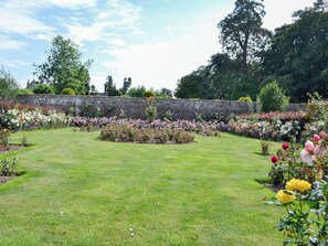 A garden with a variety of flowers and a stone wall.