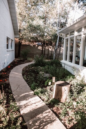 A garden pathway leading to a white building with a windowed porch.