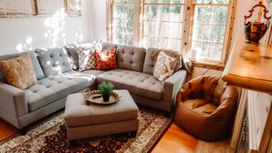 Un salón acogedor con un sofá modular, un reposapiés y un sillón de cuero marrón.