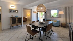 Un espace repas moderne avec une grande table, des chaises et un luminaire décoratif suspendu.