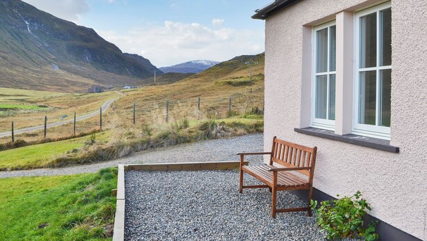 A bench outside a building with a view of a mountainous landscape. - Braigh na Leitre - UK33790 (Strathconon, Muir of Ord)