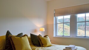 A bed with pillows, a lamp, and a window with a view. - Braigh na Leitre - UK33790 (Strathconon, Muir of Ord)