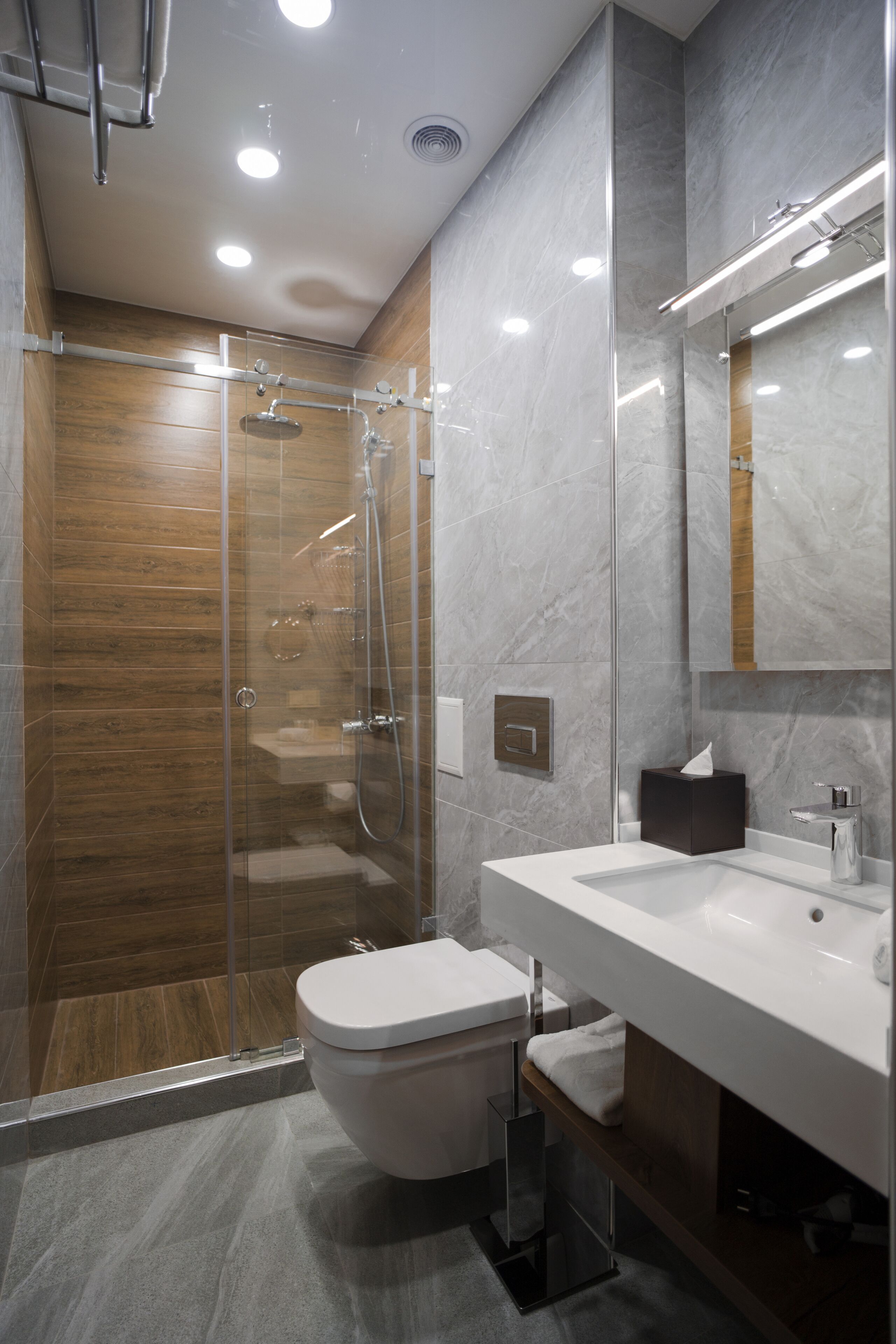 A modern bathroom with a glass-enclosed shower, a white sink, and a large mirror.