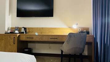 Een hotelkamer met een bed, een bureau met stoel, een televisie en een nachtkastje.