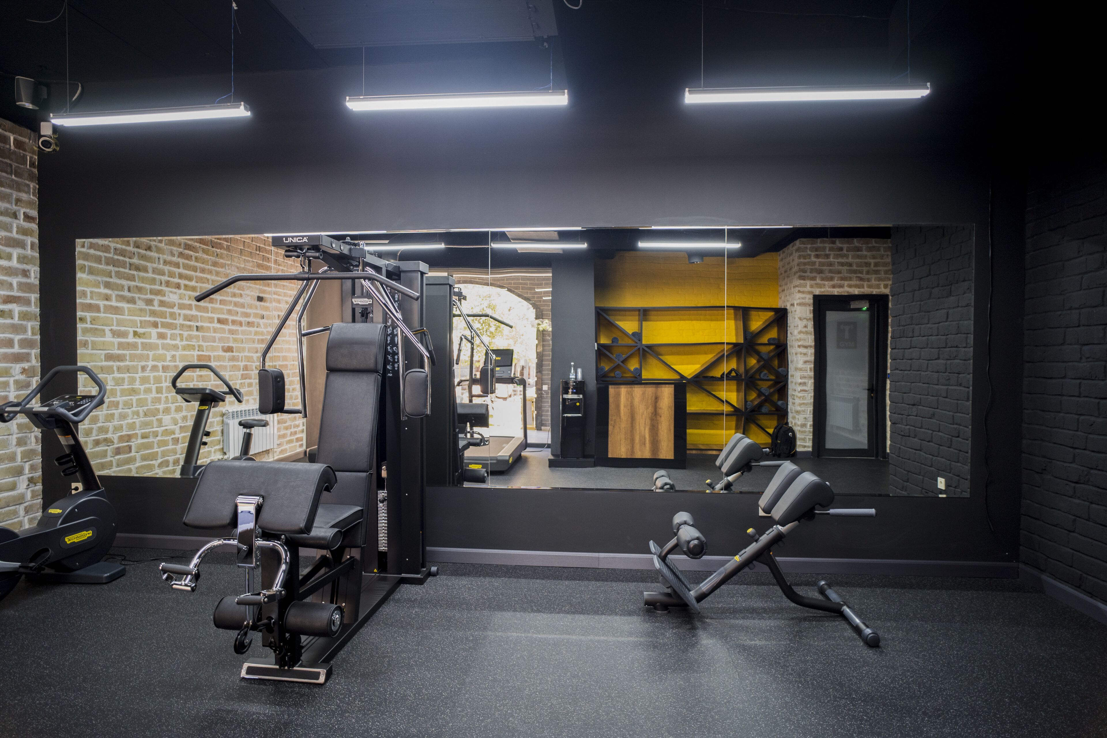 A gym with exercise equipment, a mirror, and a brick wall.