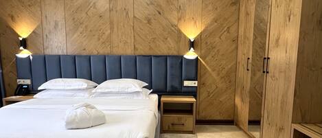 Un dormitorio con una cama grande, dos mesitas de noche, un armario y paredes de paneles de madera.
