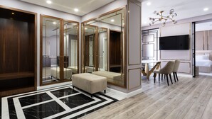 Un intérieur moderne avec un grand miroir, une armoire en bois et un coin salon équipé d’un téléviseur et d’une table.