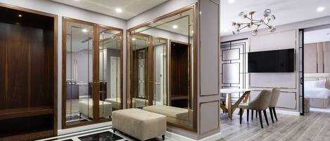 A modern interior with a large mirror, wooden wardrobe, and a seating area with a TV and a table.