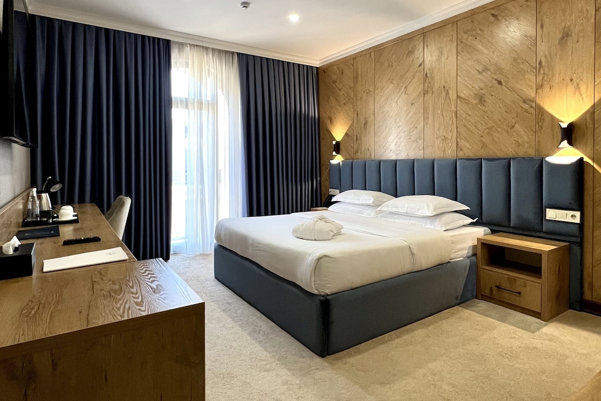 Una habitación de hotel moderna con una cama grande, un escritorio y una pared de acento de madera.